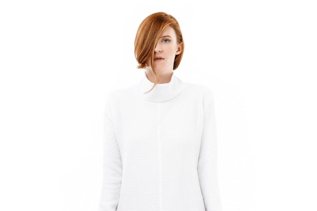 A healthcare professional demonstrating the proper layering of a medical jacket over an underscrub shirt in a clinical setting.